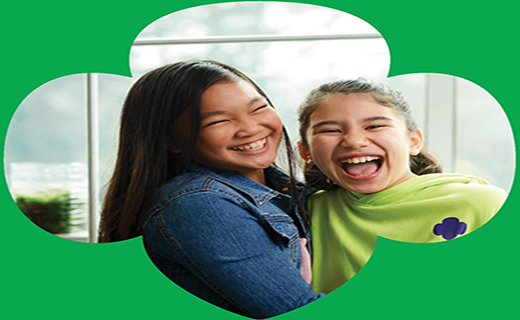 Two girls smiling inside a Girl Scouts logo